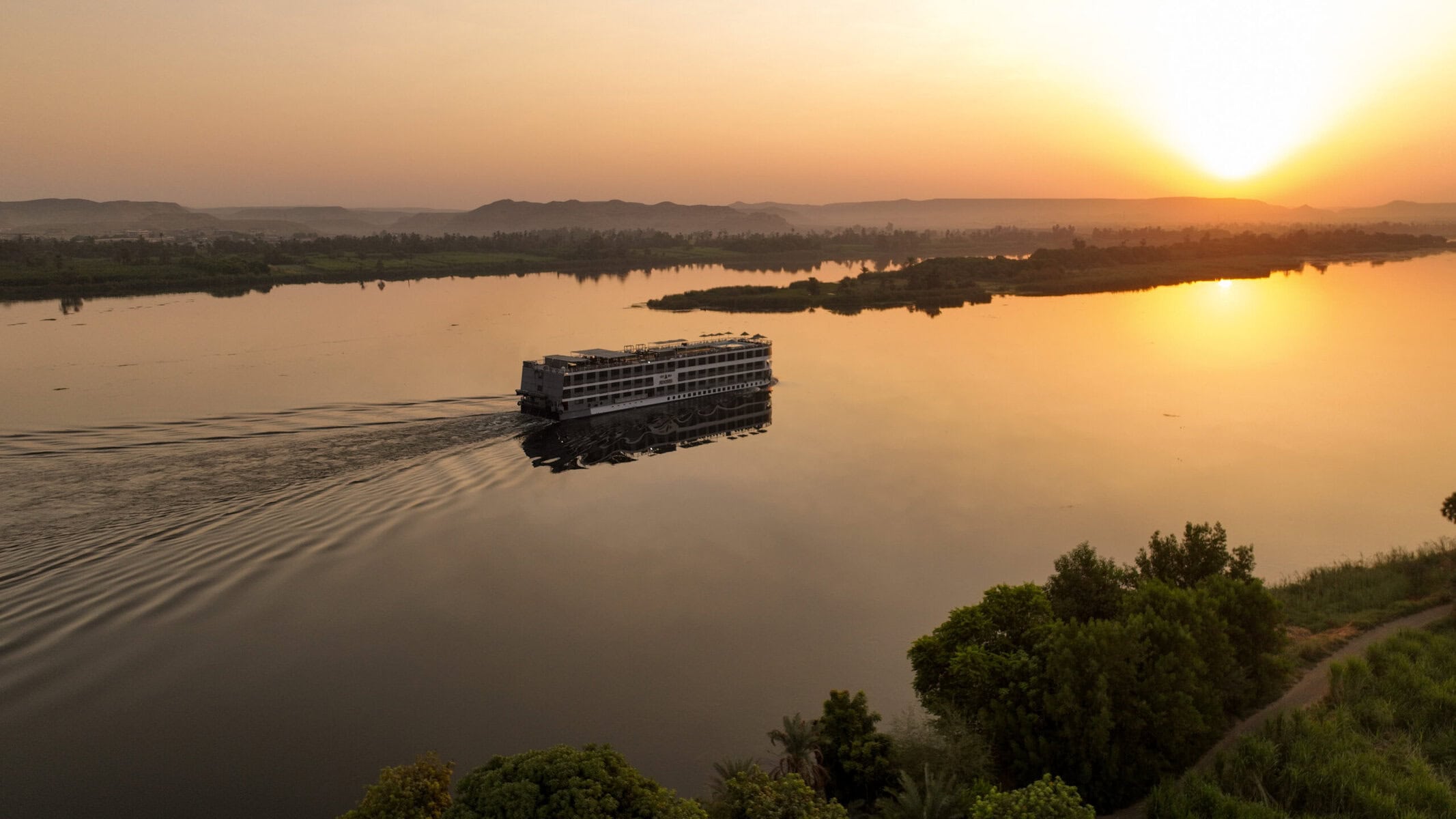 M/S City and Sea Adonis cruising the Nile River at golden sunset with green banks.