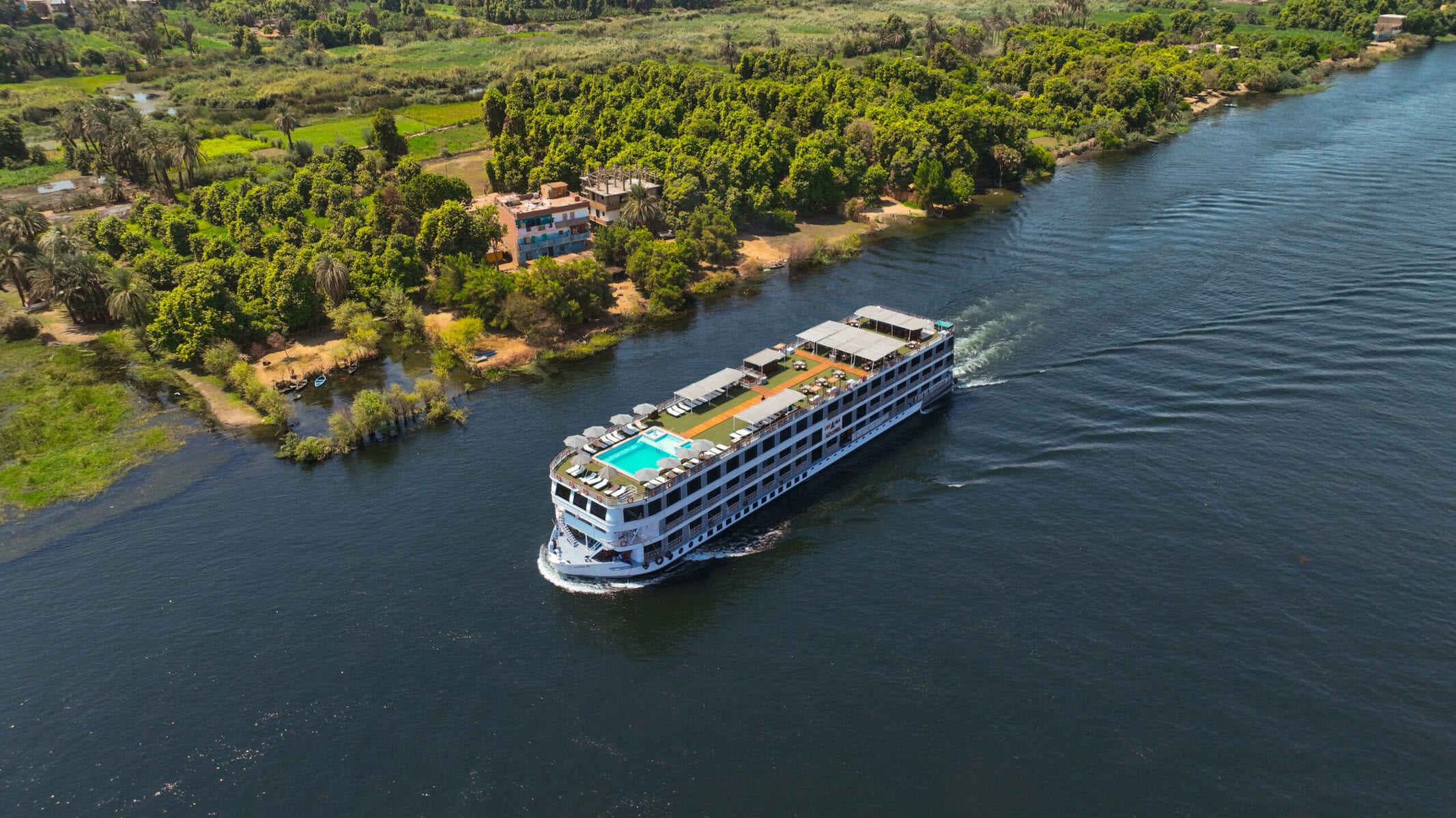 M/S City and Sea Adonis luxury Nile cruise ship sailing past lush green riverbanks and palm trees.