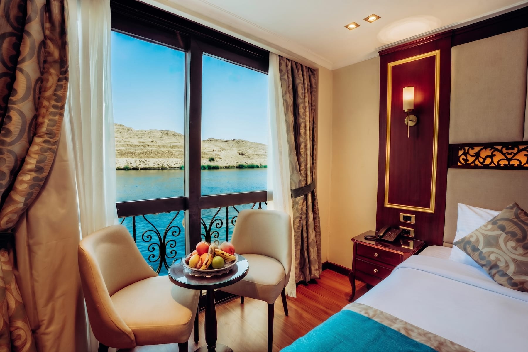 Nile-view cabin with seating area and French balcony aboard the M/S City and Sea Adonis.