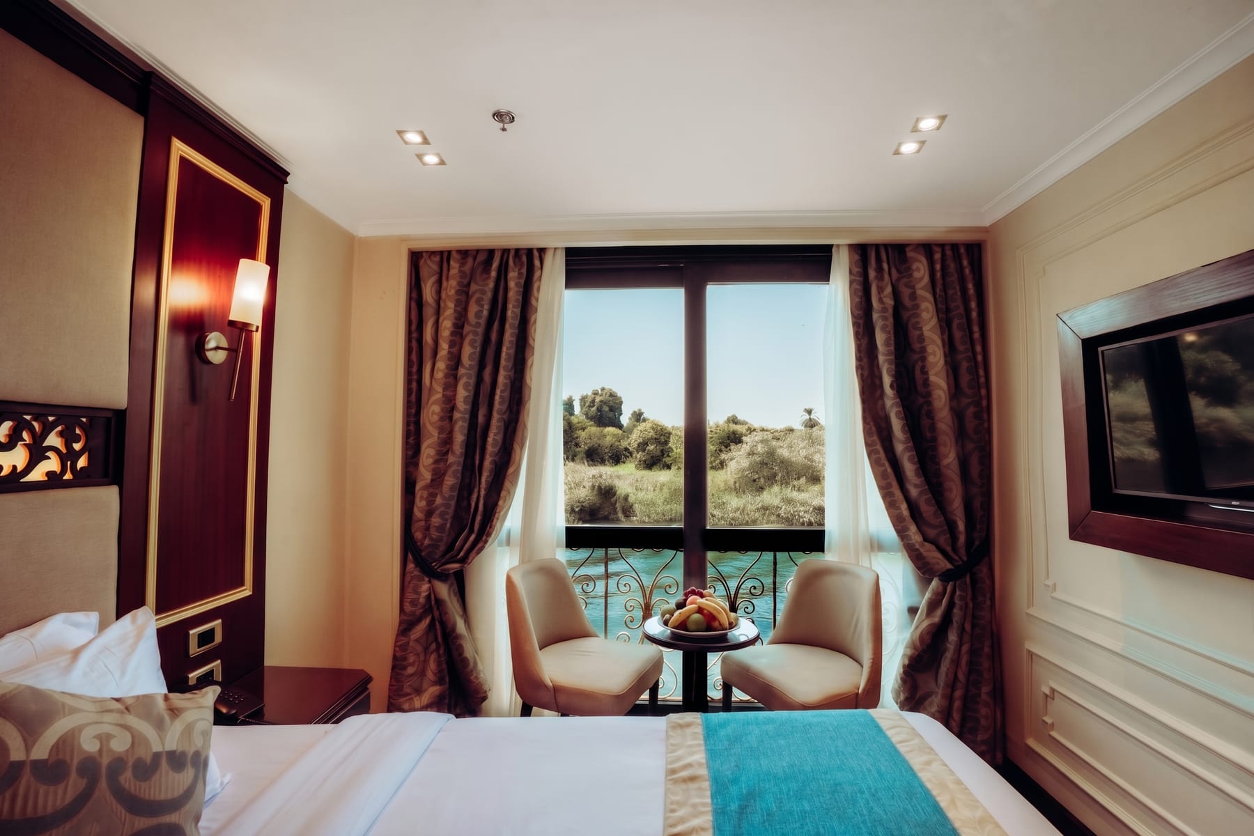 Elegant cruise cabin with a Nile view through a French balcony window aboard the M/S City and Sea Adonis.