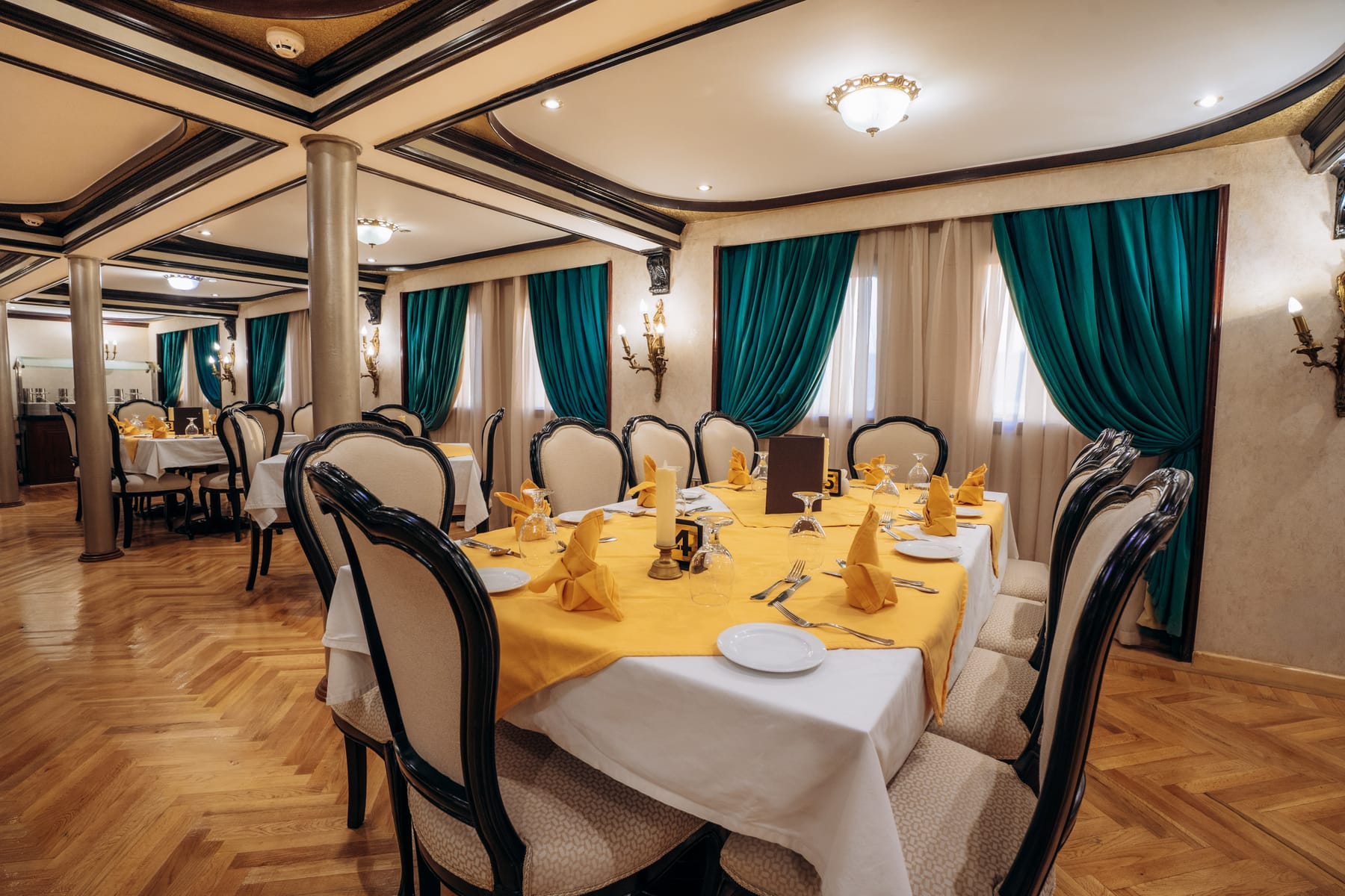 Elegant restaurant aboard the M/S City and Sea Adonis set with yellow linens and teal drapes.